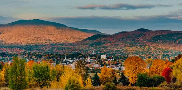 Autumn view over Rutland, Vermont: white church steeples among the foliage, with the Green Mountains behind